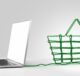 A laptop connected to a green wireframe shopping basket, symbolizing an Ecommerce Store for online shopping.